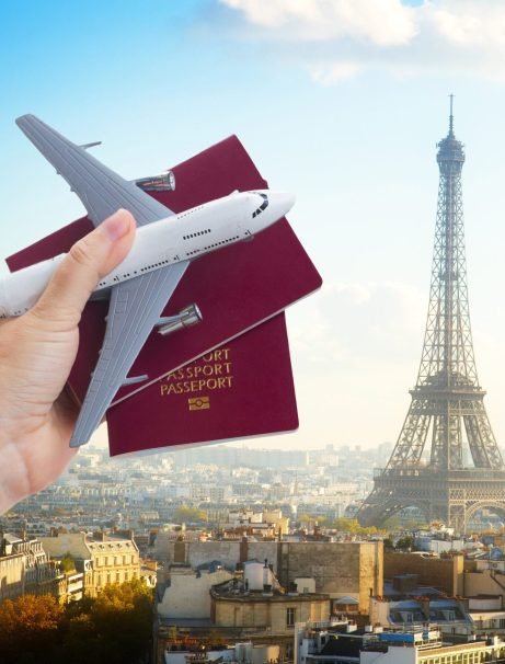 Plane travel concept, hand holding passports with plane, Paris France cityscape in background